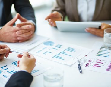 Image of business documents, pen and glasses on workplace during meeting of partners