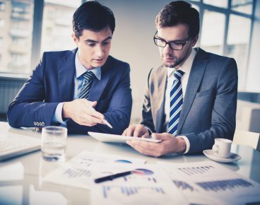 Image of two young businessmen discussing new project in office