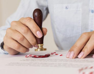 person-using-wax-seal-blurred-certificate